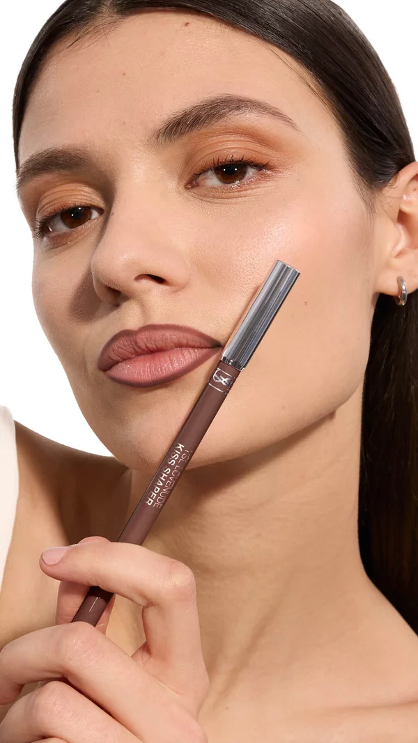 Adrienne holding YSL LOVENUDE Kiss Shaper 26 in Shade 107, full- face portrait on white background.