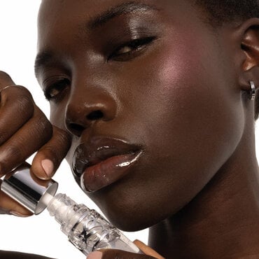 Nyaluak, YSL Beauty model, with YSL LOVESHINE Plumping Lip Oil Gloss shade 10 near her deep-toned, shimmering lips.