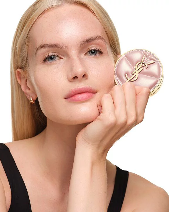 Model with fair skin holding YSL SKIN AFFAIR SOFT GLOW CUSHION. Natural-looking radiant finish and smooth skin texture.