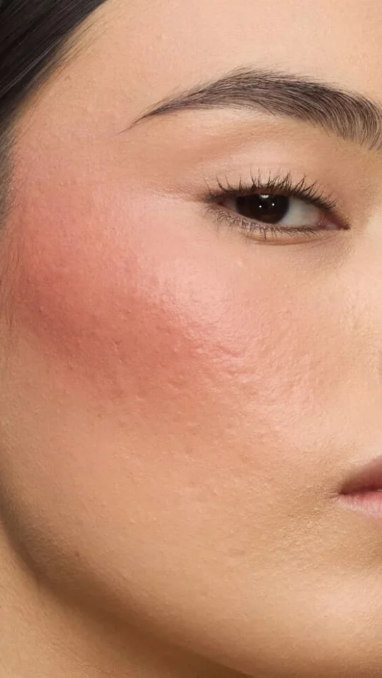 Close-up of a model's cheek wearing the Make Me Blush routine: Powder #37 Peachy Nude layered with Cream #90 Toffee Temptation for a sun-drenched glow.