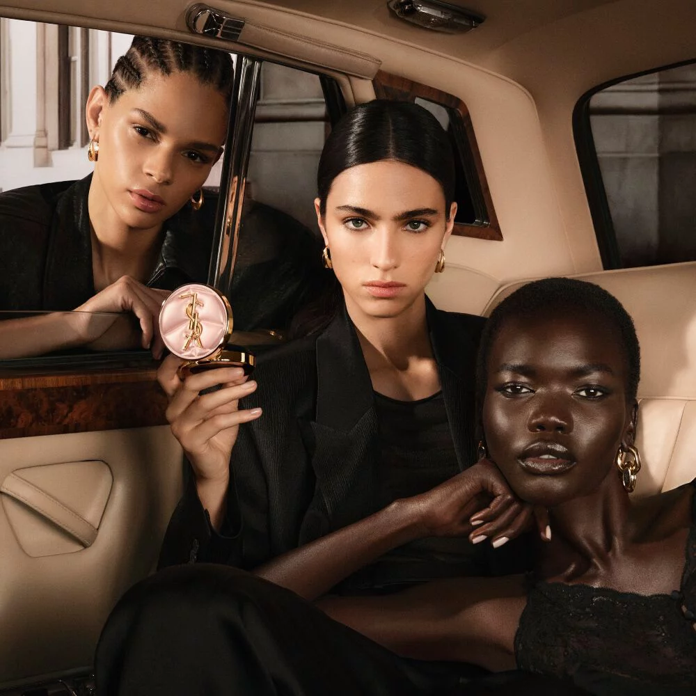 Three models in a taxi with YSL SKIN AFFAIR CUSHION. Diverse skin tones and high-fashion radiant complexions.