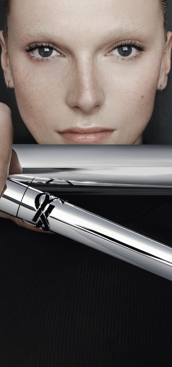 YSL Lash Latex Mascara in sleek silver packaging, showcasing rich black texture on a reflective grey background.
