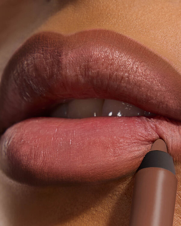 Bineta applying YSL LOVENUDE Kiss Shaper 26 in Shade 109, a close- up of her lips.