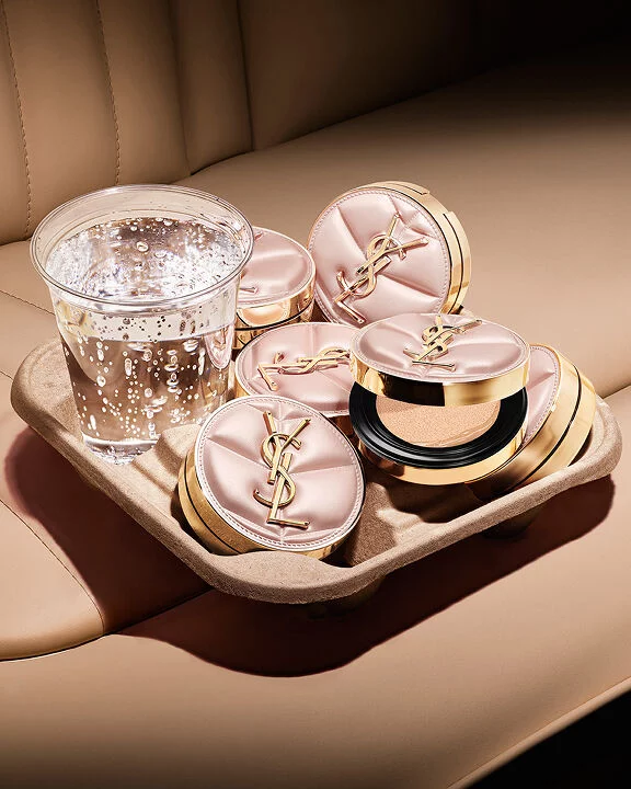YSL SKIN AFFAIR CUSHION cases in a taxi cup holder with a glass of water. Luxury on-the-go hydration and soft glow.
