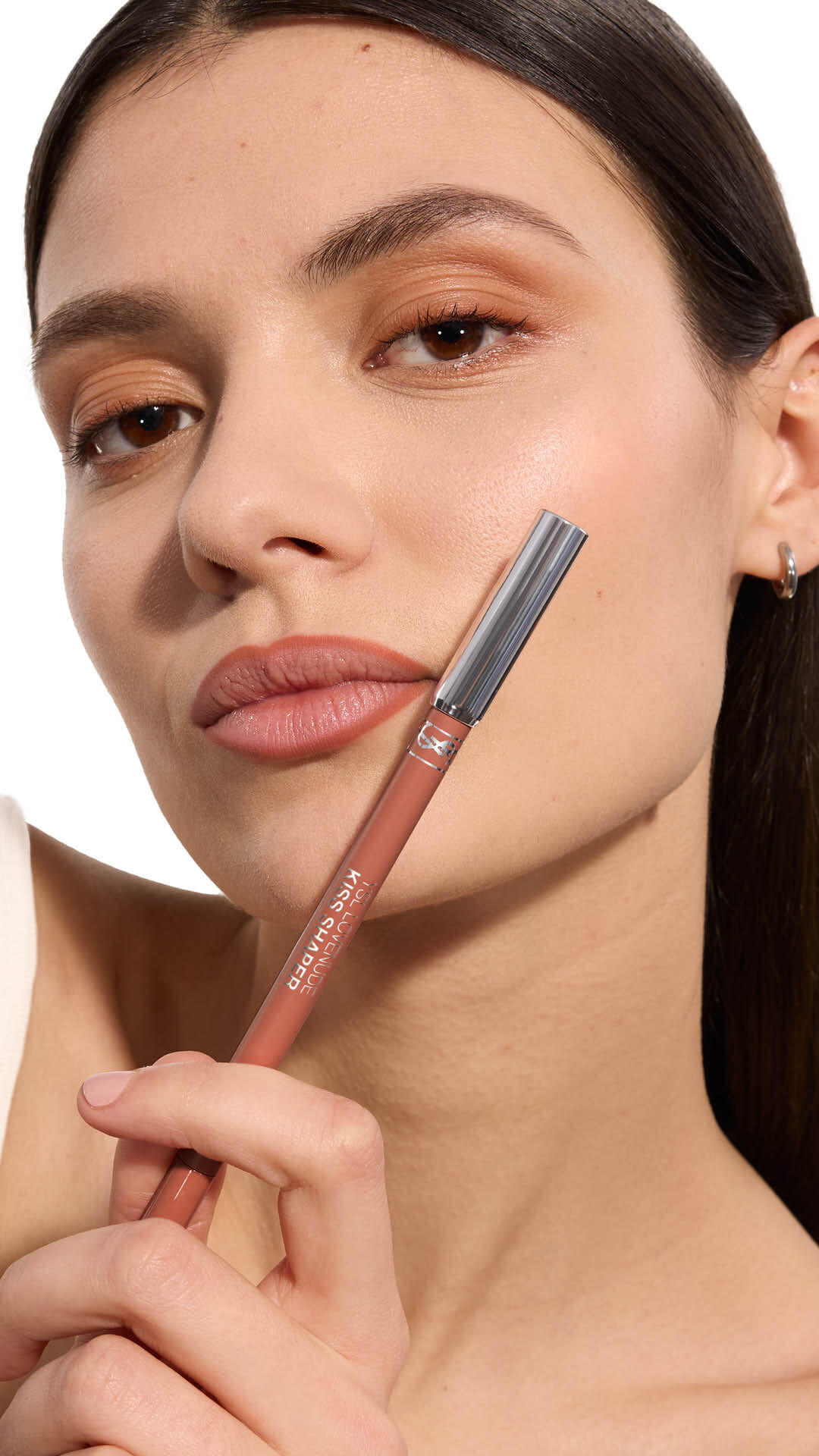 Adrienne holding YSL LOVENUDE Kiss Shaper 26 in Shade 105, full- face portrait on white background.