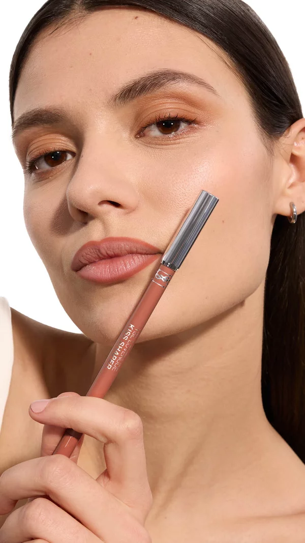 Adrienne holding YSL LOVENUDE Kiss Shaper 26 in Shade 105, full- face portrait on white background.