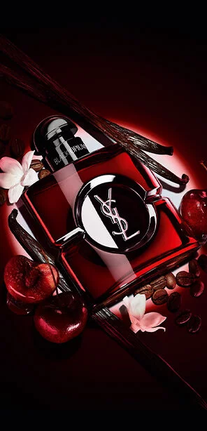Le flacon Black Opium Over Red en laque rouge profond entoure de cerises fraiches et de grains de cafe torrefies.
