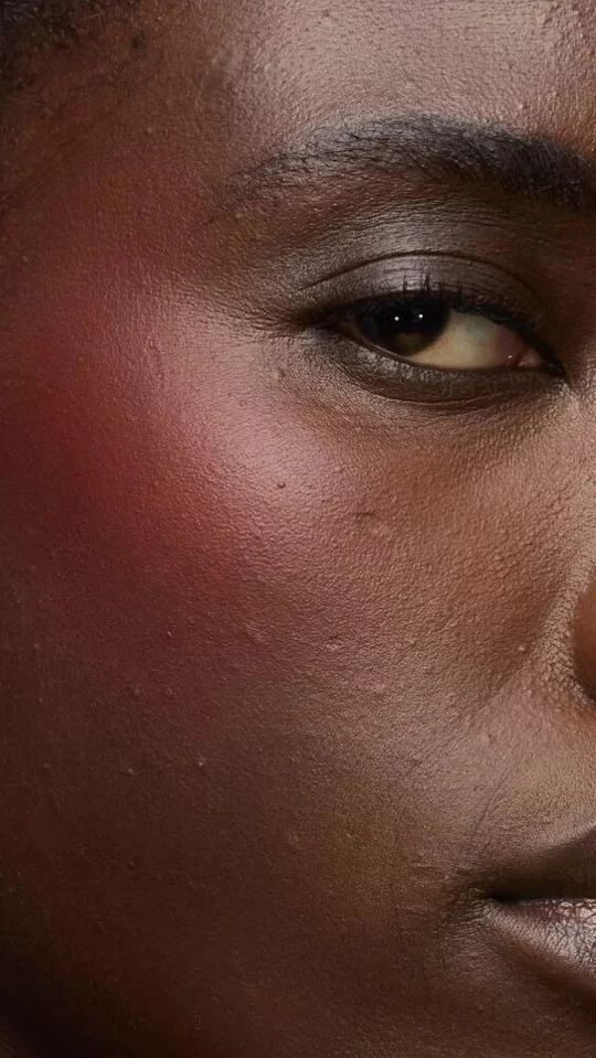 Close-up of a model's cheek wearing the Make Me Blush routine: Powder #15 Chili Crush layered with Cream #65 Strawberry Seduction for a bold, post-workout glow.