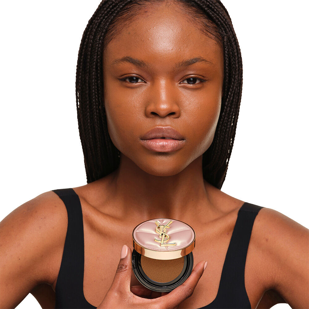 Model with a smooth, radiant complexion holding the pink YSL SKIN AFFAIR CUSHION FOUNDATION to showcase a naturally glowing, flawless skin finish.