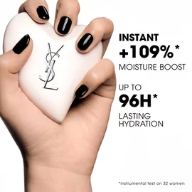 Hand with black nails holding Care Crush Hand & Body serum-in-cream, a white heart-shaped skincare accessory.