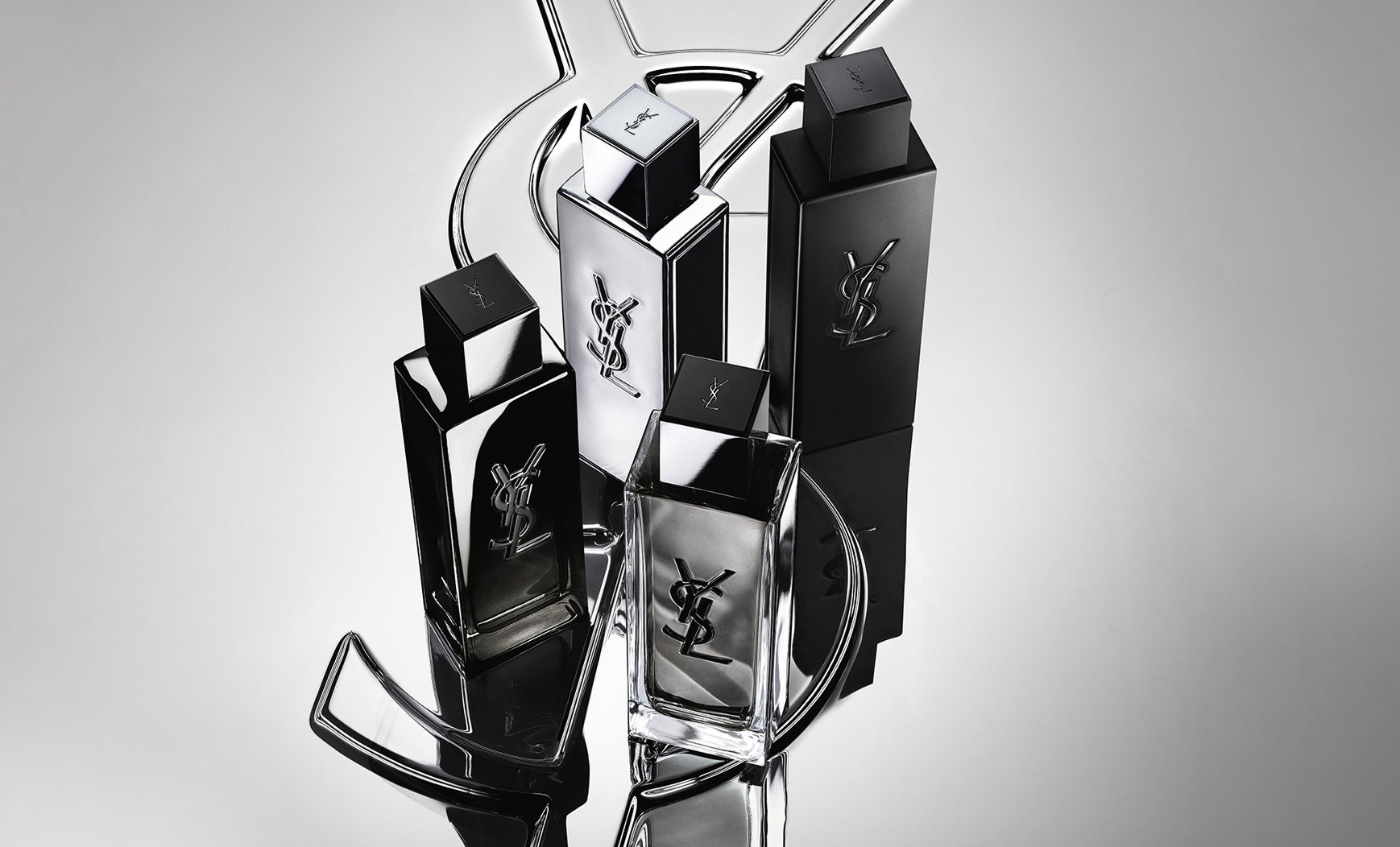 Group shot of the complete MYSLF fragrance range bottles standing on a large YSL Cassandre
logo with a reflective mirror effect.
