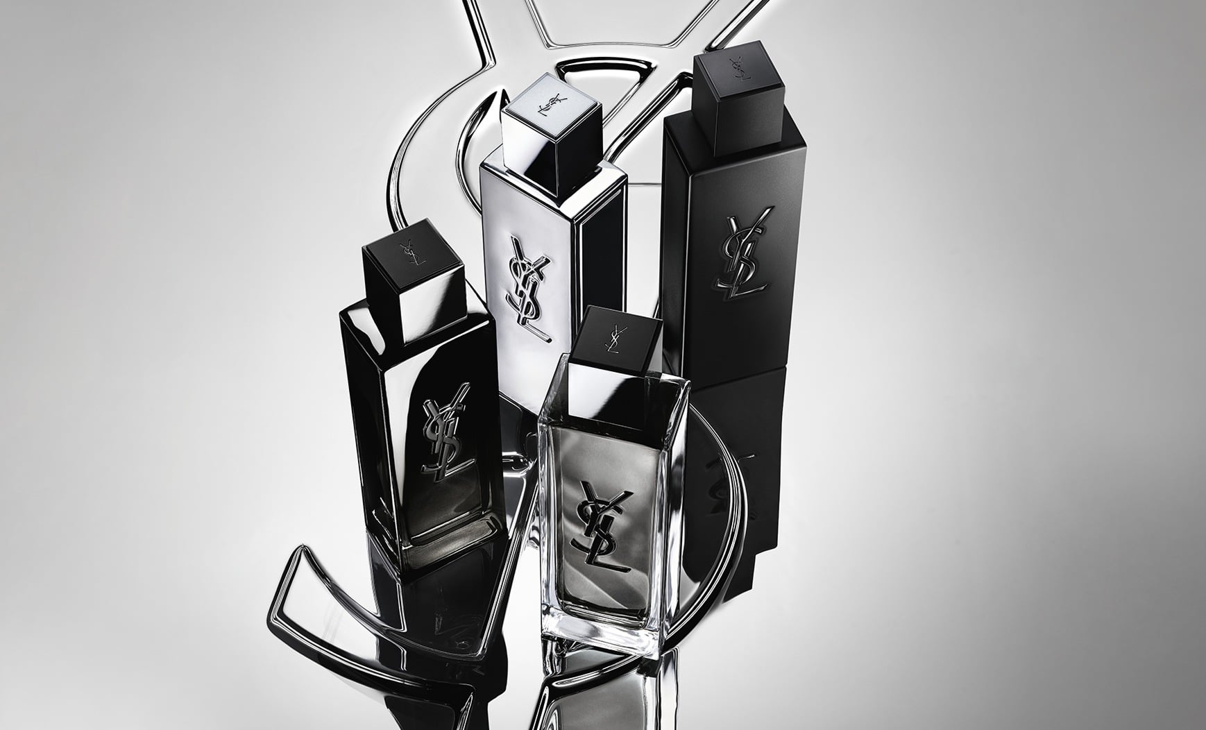 Group shot of the complete MYSLF fragrance range bottles standing on a large YSL Cassandre logo with a reflective mirror effect.