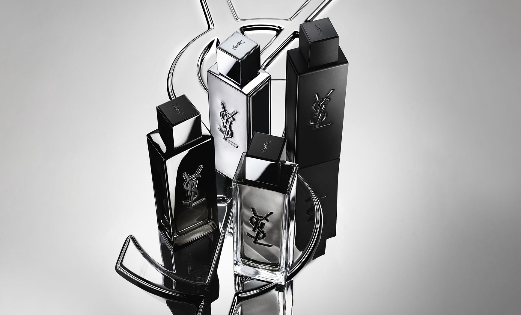 Group shot of the complete MYSLF fragrance range bottles standing on a large YSL Cassandre logo with a reflective mirror effect.