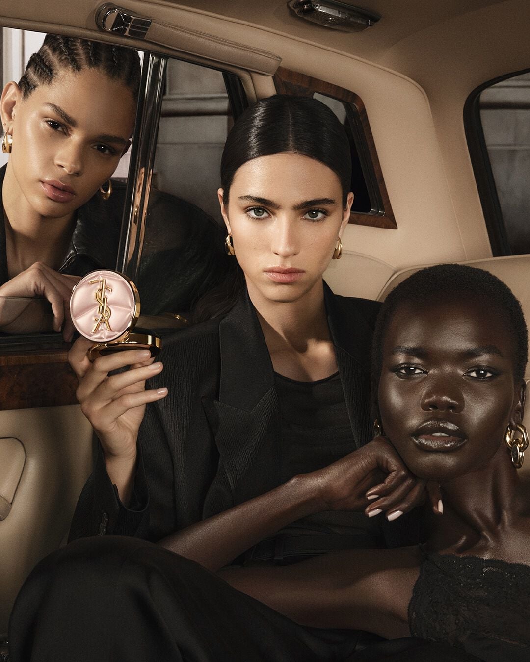 Three models in a taxi with YSL SKIN AFFAIR CUSHION. Diverse skin tones and high-fashion radiant complexions.