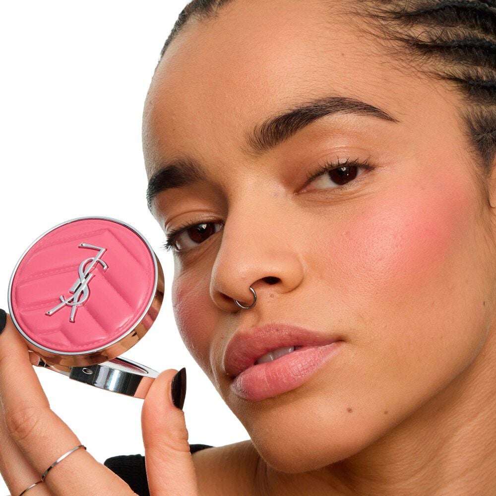 Close-up of a model holding the YSL Make Me Blush Lifted Glow Cream Blush, showing a radiant, lifted glow on her cheekbones. mieux