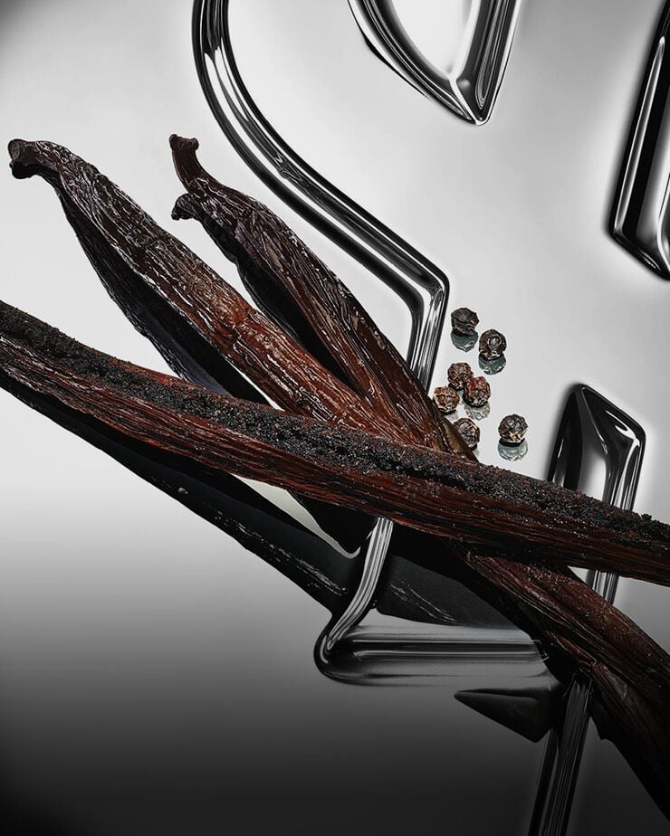A close-up photograph of multiple dark, wrinkled vanilla pods.
