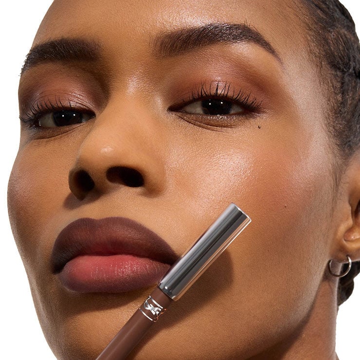 Model holding YSL LOVENUDE KISS SHAPER lip liner with defined nude lips.