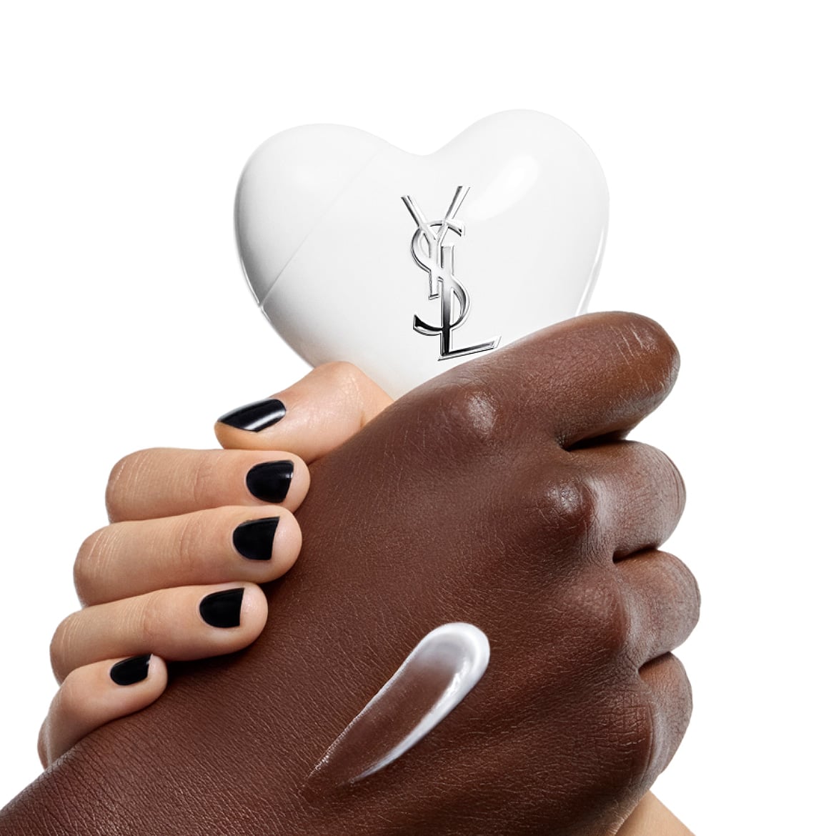 Mains à la peau foncée et claire tenant le sérum-en-crème mains et corps CARE CRUSH, avec une touche de crème blanche.