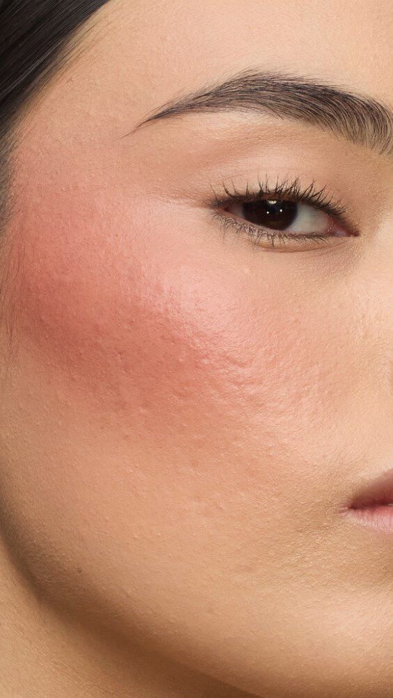 Close-up of a model's cheek wearing the Make Me Blush routine: Powder #37 Peachy Nude layered with Cream #90 Toffee Temptation for a sun-drenched glow.