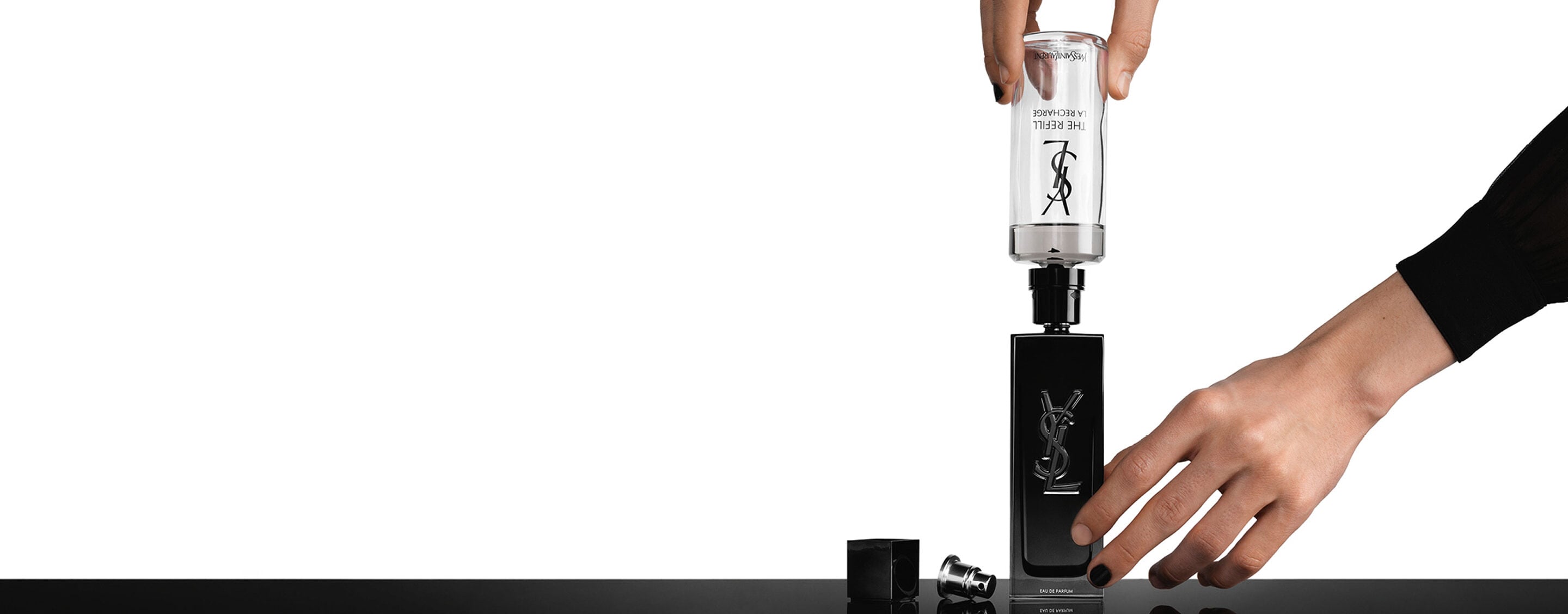 A hand pouring a glass refill bottle into a standard MYSLF bottle to illustrate the refillable system. 